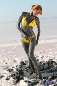 Frau im Bikini mit Soleschlickpackung am Strand