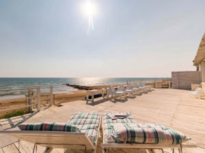 Sonnenliegen auf Holzdeck mit Blick auf das Meer