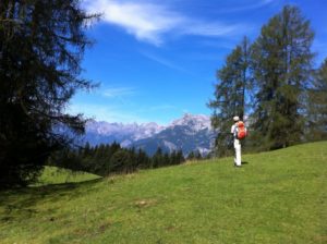 Mann mit Rucksack steht vor einer Bergkulisse