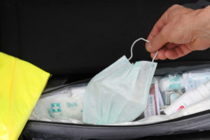 Hand legt Mundschutz in Erste-Hilfe-Koffer