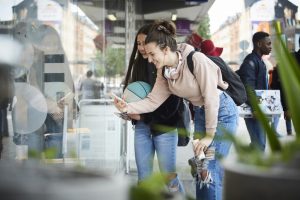 junge Frau fotografiert mit ihrem Smartphone ein Schaufenster