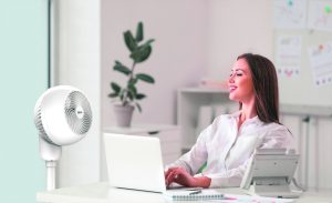 junge Frau im Büro vor einem Ventilator