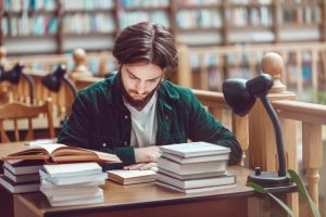 junger Mann liest in einer Bibliothek