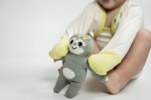 Baby spielt mit gestrickter Puppe