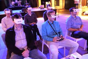 Menschen sitzen mit VR-Brillen auf Stühlen