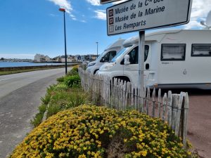 Wohnmobile auf einem Parkplatz gegenüber dem Strand